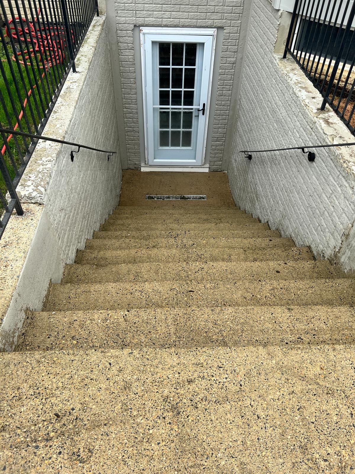 After — clean concrete stairs and walkway leading to the basement entry door