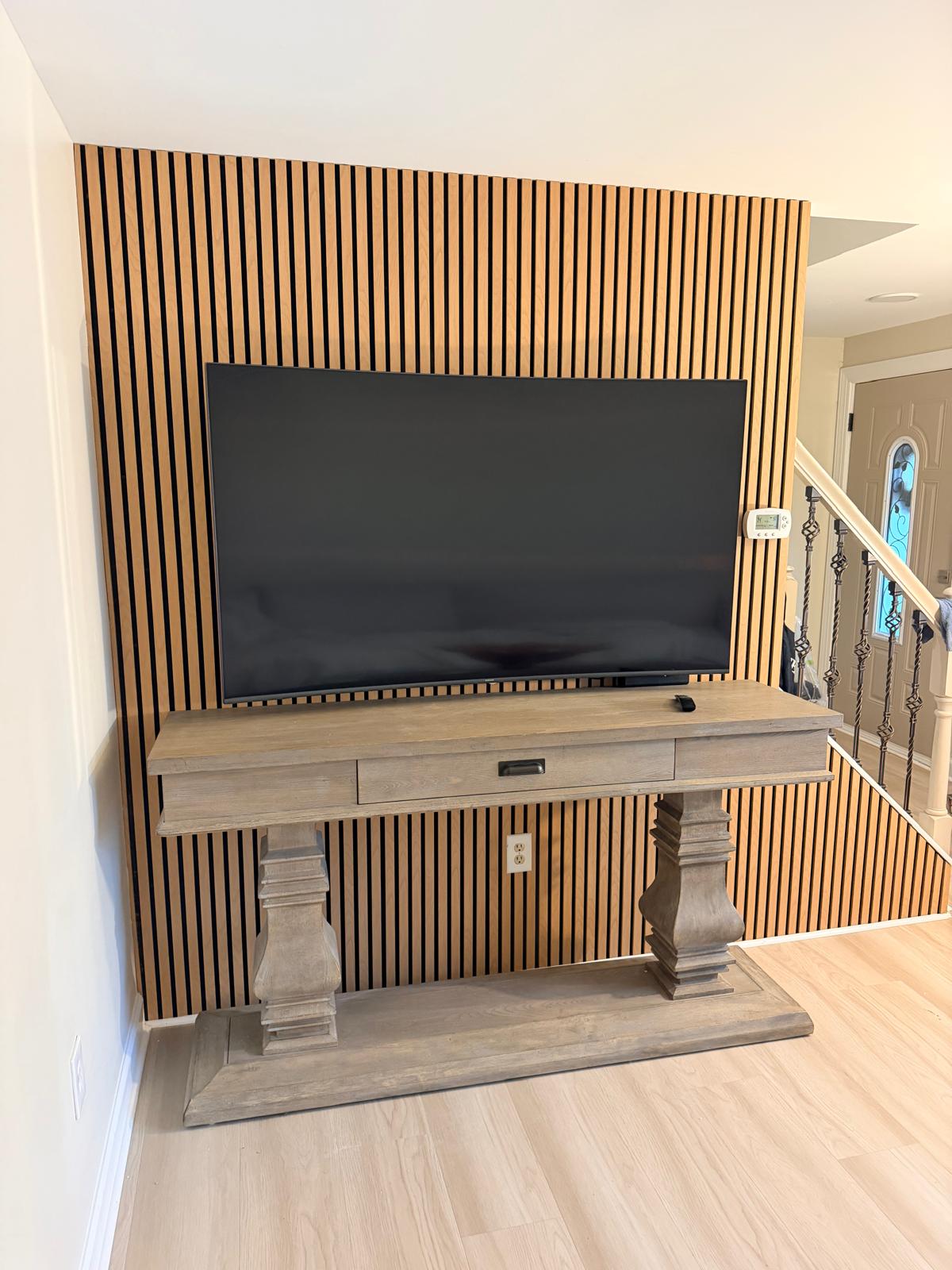 After — TV wall covered in vertical wood slats with black backing around the console