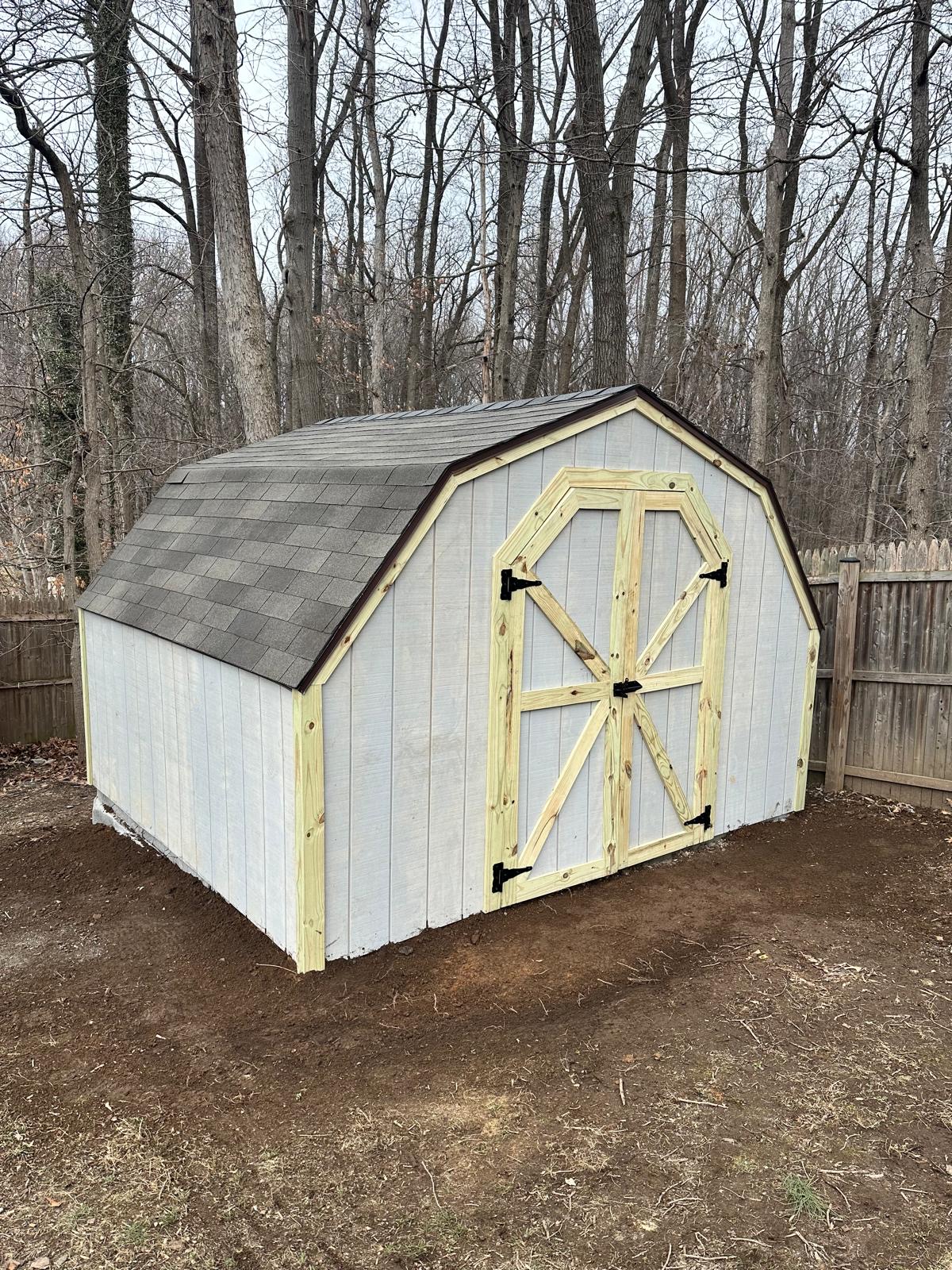 After — finished barn-style shed with gambrel roof and wooden double doors