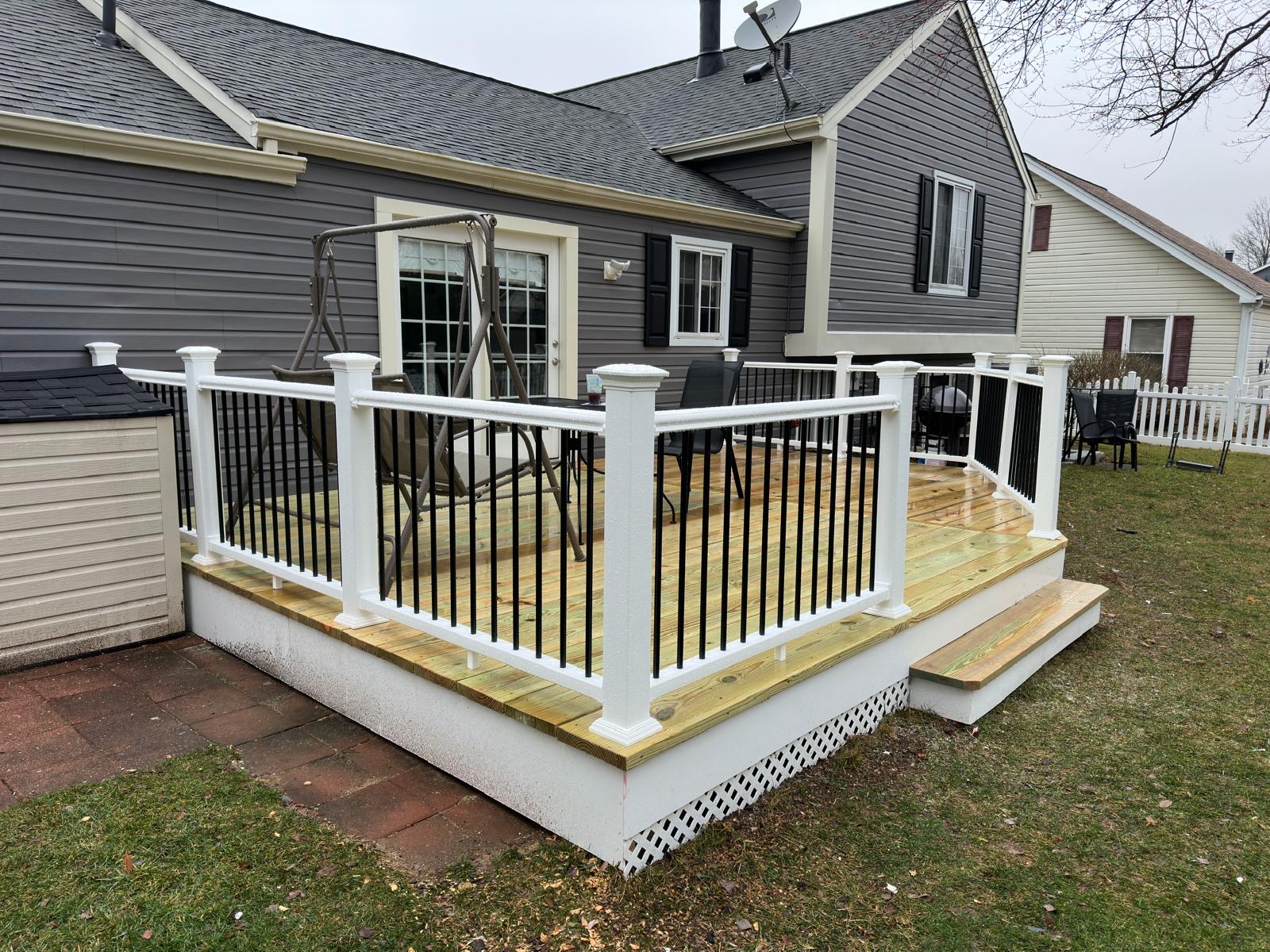 After — finished deck with white railings, black balusters and new steps