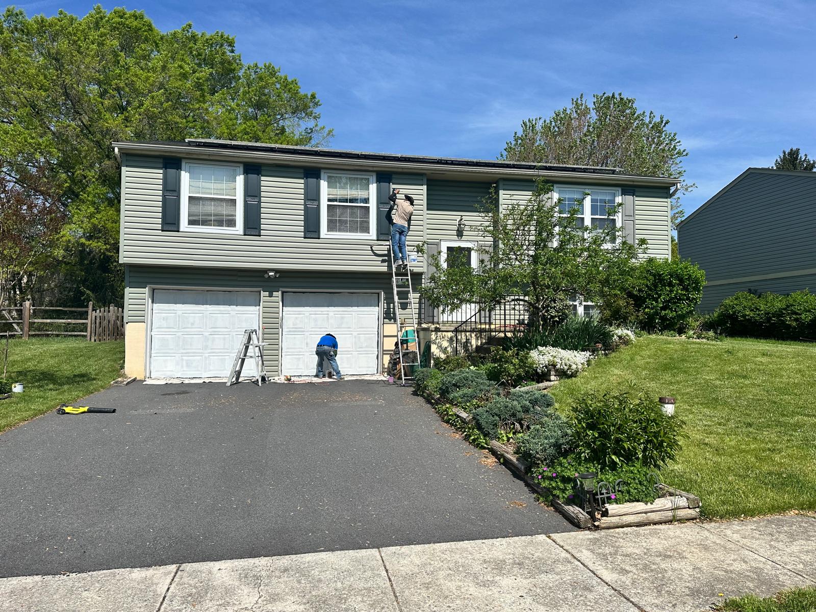 After — freshly painted siding, dark shutters and clean white garage doors
