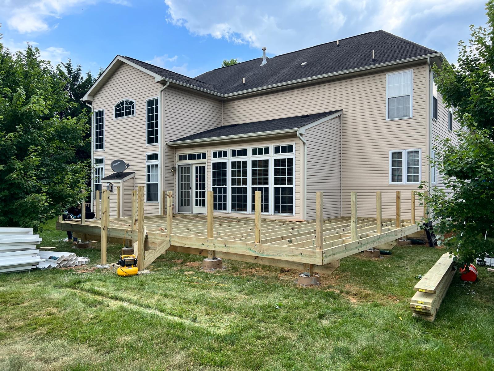 Before — new deck framing with posts and joists behind the sunroom