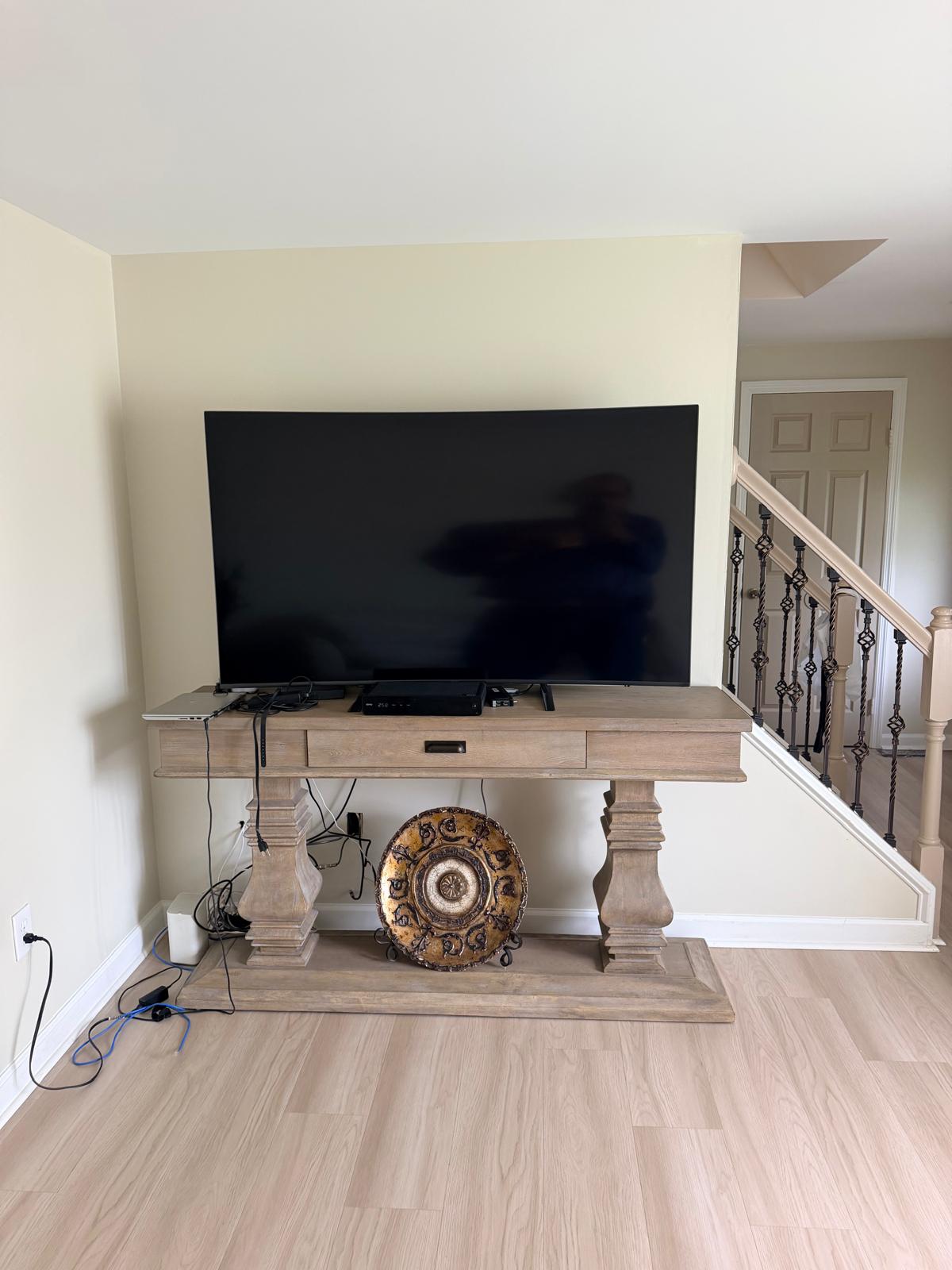 Before — TV on a plain light wall with visible cables under the console