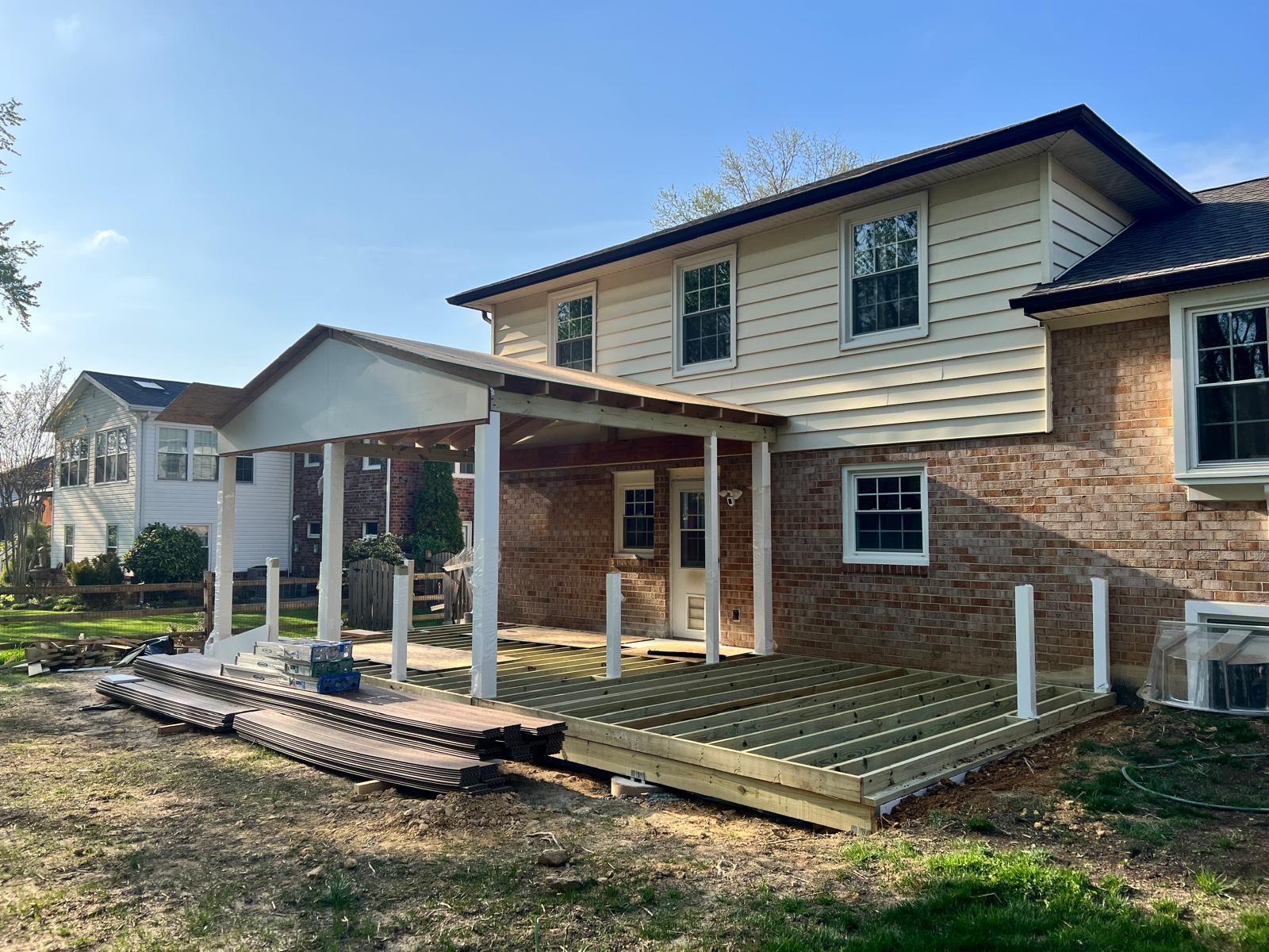 Before — porch roof framing and deck joists under construction behind the house