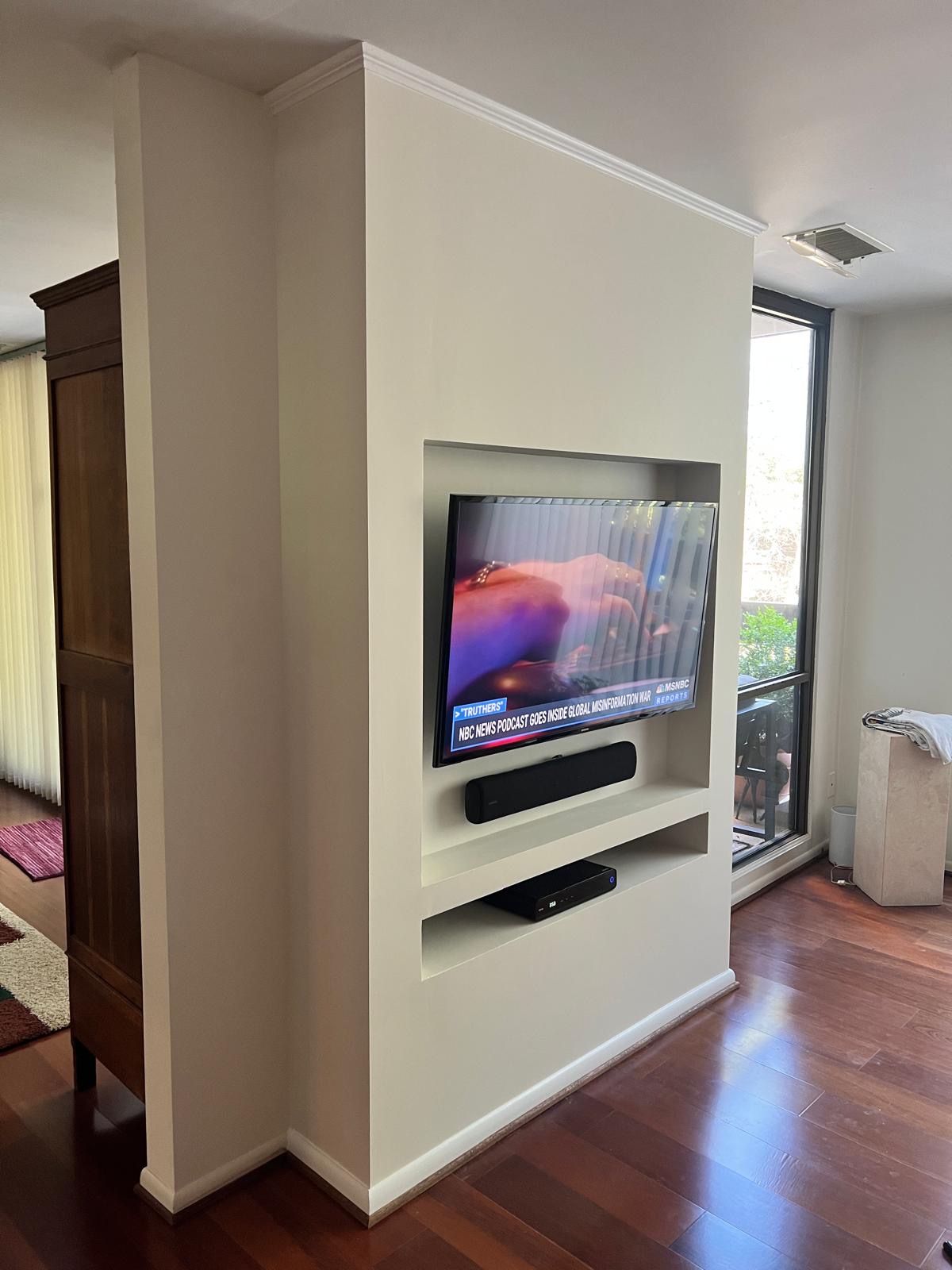 After — finished built-in wall with recessed TV niche, shelving, crown molding and fresh paint