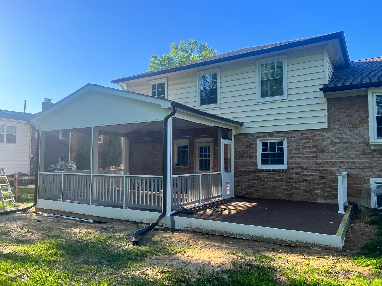 After — finished screened porch with white railings and a composite deck