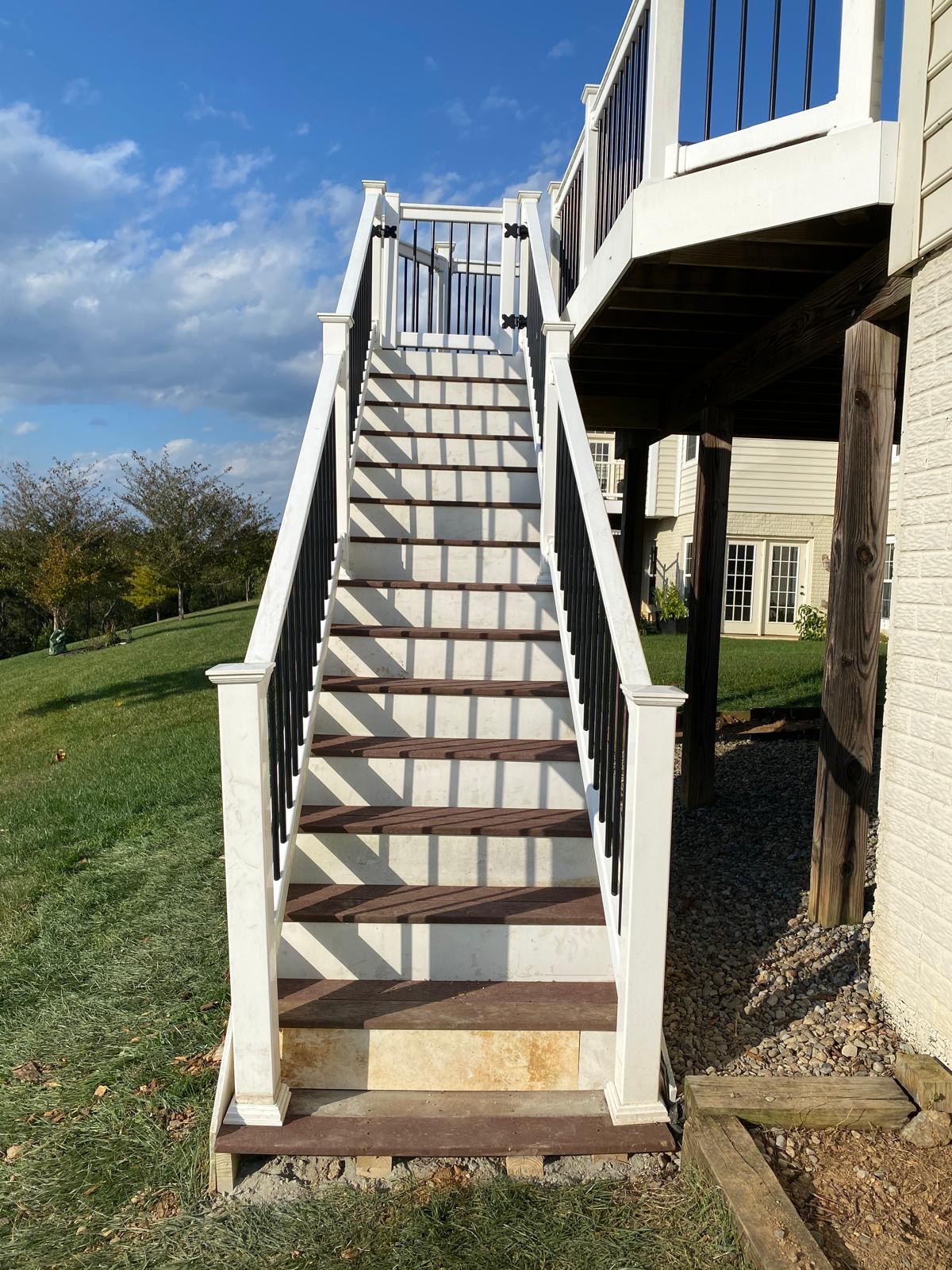 After — new composite deck stairs with white railings and black balusters